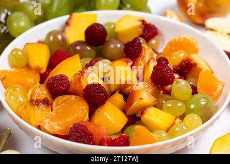 Salade de fruits avec fruits tranchés, raisins mélangés, framboises, nectarines, mandarines et pommes Banque D'Images
