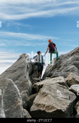 Grimpeurs mâles et femelles de haut-five au sommet de la montagne. Équipe mixte d'escalade. Banque D'Images