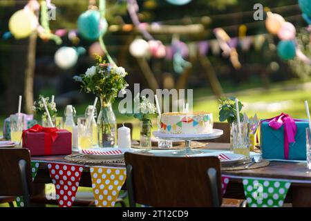 Plan de la table d'anniversaire avec des décorations colorées, gâteau d'anniversaire, et cadeaux. Inspiration pour une décoration d'anniversaire simple et de bon goût pour un jardin Banque D'Images