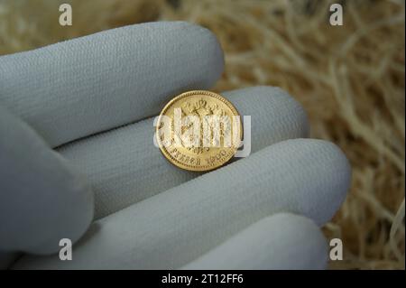 Une pièce d'or de l'Empire russe dans la main d'un numismatiste. Numismatique et investissements. Banque D'Images