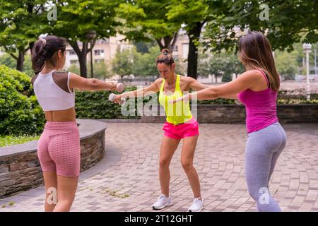 Fille Latina faisant du sport dans un parc dans la ville, mode de vie une vie saine, élèves enseignants s'exerçant avec des poids Banque D'Images