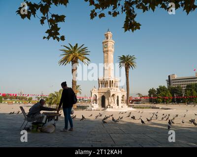 Izmir, Turquie. 5 octobre 2023. La célèbre tour de l'horloge d'Izmir, les vendeurs traditionnels d'aliments pour pigeons. Un matin d'automne dans le centre-ville du quartier de Konak. Banque D'Images