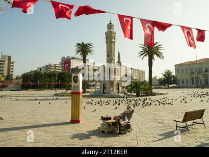 Izmir, Turquie. 5 octobre 2023. La célèbre tour de l'horloge d'Izmir, les vendeurs traditionnels d'aliments pour pigeons. Un matin d'automne dans le centre-ville du quartier de Konak. Banque D'Images