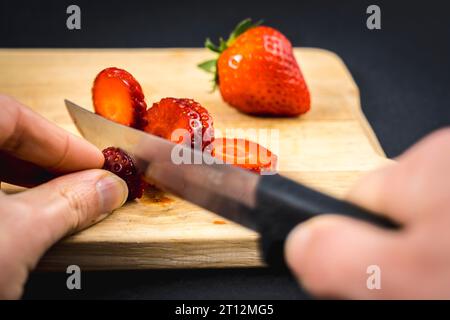 Nous commençons par couper une fraise sur un bois, une recette de fraises maison Banque D'Images