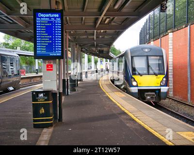 Un train de banlieue local arrive à un quai vide à Lanyon place Station à Belfast, Irlande du Nord, Royaume-Uni. Un affichage indique l'heure à 0801 Banque D'Images