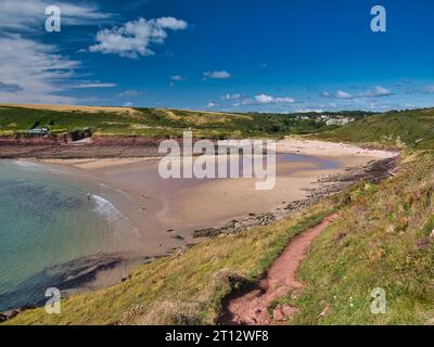 L'étendue sablonneuse de Manorbier Beach dans le Pembrokeshire au pays de Galles, Royaume-Uni. Pris sur une journée ensoleillée en été avec un petit nombre de touristes profitant du bleu s Banque D'Images