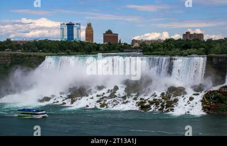 Maid of the Mist bateau de croisière traversant American Falls dans les eaux des chutes du Niagara avec la rivière Niagra et les bâtiments à New York dans le backgro Banque D'Images