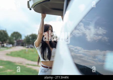 Femme a ouvert le coffre de la voiture pour décharger ses bagages après être arrivée à la propriété Banque D'Images