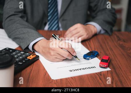 Homme signant l'accord de contrat de document d'assurance automobile. Acheter ou vendre un véhicule neuf ou d'occasion. Banque D'Images