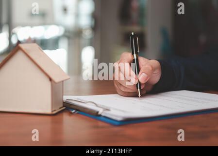 Homme d'affaires signant un contrat pour acheter une maison ou un agent immobilier. Investissement et prêt bancaire ou assurance habitation. Banque D'Images