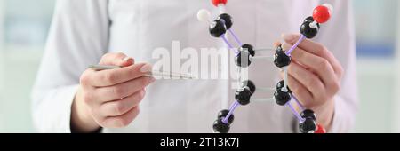 Femme en blouse de laboratoire montre un modèle de molécule dans les mains Banque D'Images