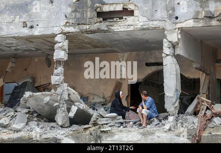 Gaza, Palestine. 10 octobre 2023. Des Palestiniens sont assis parmi les décombres d'un immeuble résidentiel endommagé, à la suite des frappes israéliennes, dans la ville de Gaza. Israël a déclaré qu'il avait repris les zones frontalières de Gaza au Hamas alors que le nombre de morts de la guerre dépassait les 3 000 le 10 octobre, quatrième jour de combats exténuants depuis que les islamistes avaient lancé une attaque surprise. (Photo Ahmed Zakot/SOPA Images/Sipa USA) crédit : SIPA USA/Alamy Live News Banque D'Images