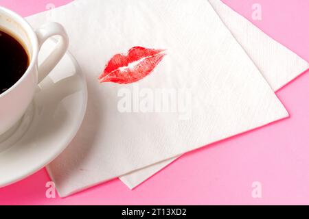 Une serviette avec un baiser et une tasse de café sur fond rose Banque D'Images