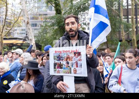 New York, États-Unis. 10 octobre 2023. Evyatar Shamsiev tenant un drapeau israélien et des photos de citoyens kidnappés par le Hamas assiste à une veillée et à un rassemblement "New York stands with Israel" le 10 octobre 2023 à New York. Partout dans le pays et dans le monde, des partisans d’Israël assistent à des rassemblements pour montrer leur soutien à Israël après les attaques perpétrées le week-end dernier par des militants palestiniens qui ont fait des centaines de morts parmi les civils et plus d’une centaine d’otages pris à Gaza. Crédit : SOPA Images Limited/Alamy Live News Banque D'Images