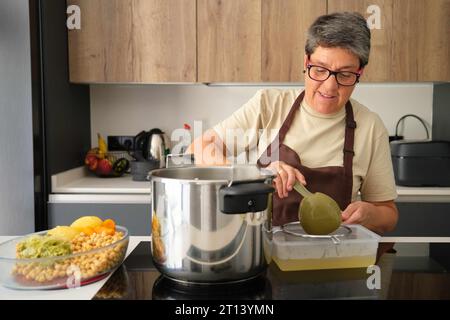 Femme espagnole mature tentant le stock du cocido madrileño, plat typiquement espagnol. Banque D'Images