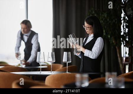 Portrait vue de côté de jeune femme asiatique polir verre à vin dans le cadre d'un restaurant de luxe, espace de copie Banque D'Images