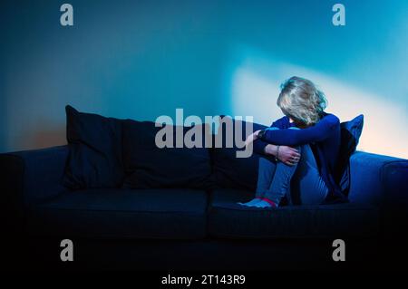 PHOTO POSÉE PAR Un MANNEQUIN photo de dossier datée du 09/03/15 d'une femme assise sur un canapé. Près de 7 000 personnes ont été détenues pour des soins et un traitement de santé mentale obligatoires en Écosse au cours de la dernière année, montrent de nouveaux chiffres de la Mental Welfare Commission. En Écosse, le nombre de personnes détenues pour des soins et un traitement de santé mentale obligatoires est passé à 6 713 en 2022-23, tandis que le nombre de garanties a diminué. Cela représente une hausse de 1,7 % par rapport à l'année précédente et est conforme aux chiffres en hausse à plus long terme, passant de 4 530 détentions en 2013-4.Date de publication : mercredi 11 octobre 2023. Banque D'Images