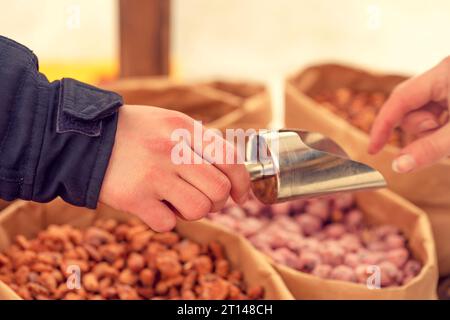 Une main avec une pelle et une main prennent des noix. noix mélangées noisettes, noix, noix de cajou, pignons de pin sur fond. gros plan. arachides, noyau, noisette, nu Banque D'Images