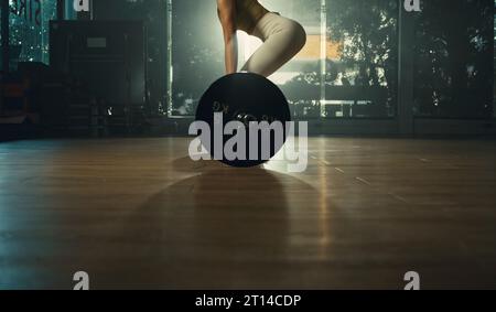 Jeune femme faisant le soulevé de terre avec la barre lourde dans la salle de gym, athlète féminine forte avec le corps musclé soulevant des poids, l'exercice avec barre. Banque D'Images