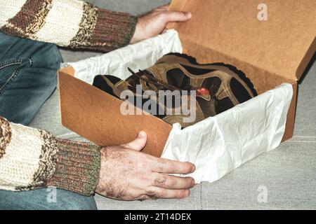 L'homme tient une boîte avec des chaussures dans les mains. Concept d'achat, d'essayer des chaussures et des bottes.gros plan. Banque D'Images