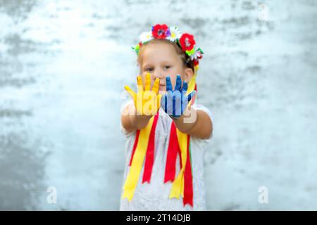 Enfant fille portant la Wheath avec des rubans montrent les mains peintes dans les couleurs de drapeau ukrainien - jaune et bleu , se concentrer sur les mains. Jour de l'indépendance de l'Ukraine, FL Banque D'Images