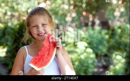 Mignonne petite fille mange de la pastèque. Mise au point sélective. Banque D'Images