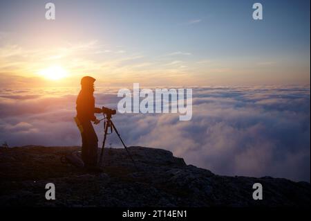 Une jeune femme faisant un film dans les montagnes brumeuses au coucher du soleil. Banque D'Images