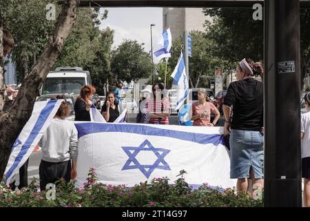 Jérusalem, Israël. 11 octobre 2023. Procession funéraire pour le Sgt Adi Tzur de la brigade Golani de Tsahal quitte la maison familiale alors que des centaines de personnes tapissent la rue avec des drapeaux israéliens pour leur rendre hommage et leur remercier pour son sacrifice. Tzur faisait partie des centaines de disparus suite aux tirs massifs de roquettes depuis la bande de Gaza sur Israël le 7 octobre 2023, à l’infiltration d’hommes armés en territoire israélien, au massacre de femmes et d’enfants civils dans leurs maisons et à la prise d’otages de civils et de soldats. Israël est engagé dans une guerre avec le Hamas de la bande de Gaza. 300 000 réservistes ont été déployés et le si Banque D'Images