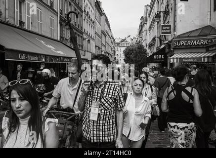 Un guide touristique tient un parapluie alors qu'il mène un groupe de touristes à travers le quartier Latin bondé de Paris, en France. Banque D'Images