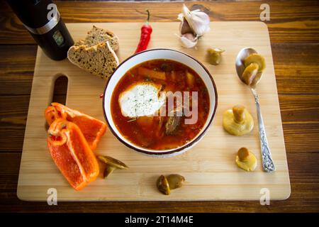 Soupe végétarienne cuite de betteraves avec des champignons et d'autres légumes dans un bol avec des épices, sur une table en bois. Banque D'Images