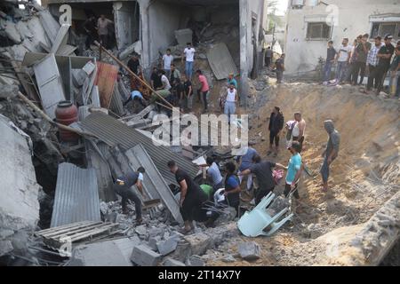 Gaza. 11 octobre 2023. Les gens recherchent des survivants parmi les décombres d’un bâtiment après une frappe aérienne israélienne dans la ville de Khan Younis, dans le sud de la bande de Gaza, le 11 octobre 2023. Crédit : Yasser Qudih/Xinhua/Alamy Live News Banque D'Images