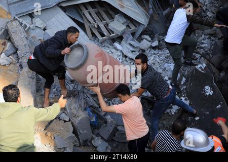 Gaza. 11 octobre 2023. Les gens recherchent des survivants parmi les décombres d’un bâtiment après une frappe aérienne israélienne dans la ville de Khan Younis, dans le sud de la bande de Gaza, le 11 octobre 2023. Crédit : Yasser Qudih/Xinhua/Alamy Live News Banque D'Images