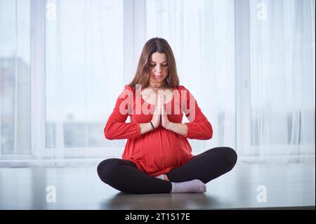 Jeune belle femme enceinte faisant yoga asana Padmasana - lotus pose à la maison. prise de vue en studio. Banque D'Images