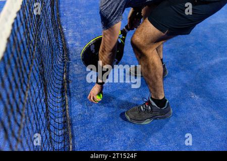 Homme jouant un jeu de padel dans un court bleu avec sa raquette Banque D'Images
