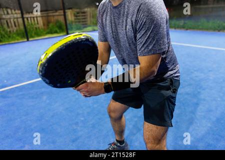 Homme jouant un jeu de padel dans un court bleu avec sa raquette Banque D'Images