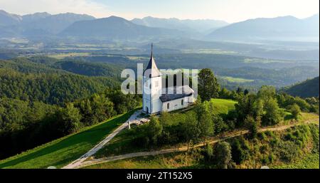 Perspective aérienne, lever de soleil sur St. Église Primoz à Jamnik sur une colline slovène luxuriante, Kranj, Gorenjska Banque D'Images