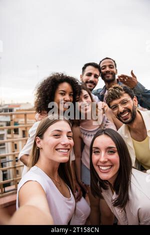Groupe multiculturel joyeux d'amis insouciants prenant un selfie dans une partie sur le toit.multiracial belles jeunes gens heureux souriant tout en prenant un Banque D'Images