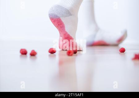 Écrasement de baies juteuses pied humain. Taches de framboise sales sur les vêtements blancs. concept de coloration de la vie quotidienne. Banque D'Images