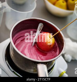 Tremper la pomme de bonbon dans un bol en verre avec du caramel. Banque D'Images