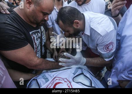 Gaza City, Territoires palestiniens. 11 octobre 2023. Les ambulanciers paramédicaux palestiniens pleurent leur camarade ambulancier Abdullah Awad, tué par des frappes aériennes israéliennes à la frontière alors qu’il soignait un groupe de blessés. Crédit : Mohammed Talatene/dpa/Alamy Live News Banque D'Images