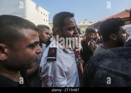 Gaza City, Territoires palestiniens. 11 octobre 2023. Les ambulanciers paramédicaux palestiniens pleurent leur camarade ambulancier Abdullah Awad, tué par des frappes aériennes israéliennes à la frontière alors qu’il soignait un groupe de blessés. Crédit : Mohammed Talatene/dpa/Alamy Live News Banque D'Images