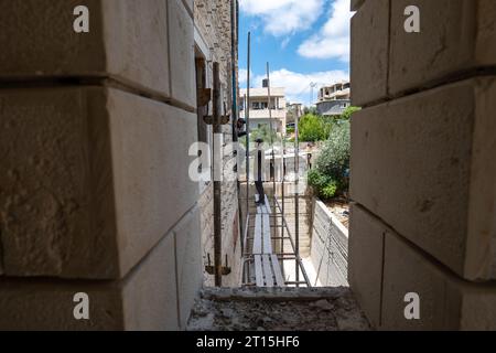 Bayt Surik, Palestine – 19 juin 2023 : deux hommes arabes de la construction se tiennent debout sur une structure d'échafaudage métallique et Stare Banque D'Images