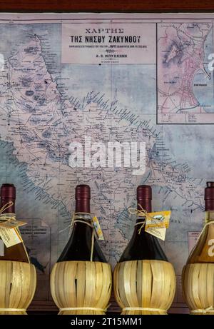 rangée de bouteilles de vin grec traditionnel dans des paniers devant une carte de zante ou zakynthos en grèce. Banque D'Images