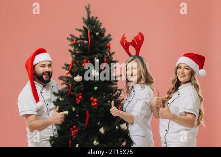 Le concept de la cuisine et des vacances de Noël. Un groupe de cuisiniers décore un sapin de Noël avec des légumes frais. Banque D'Images