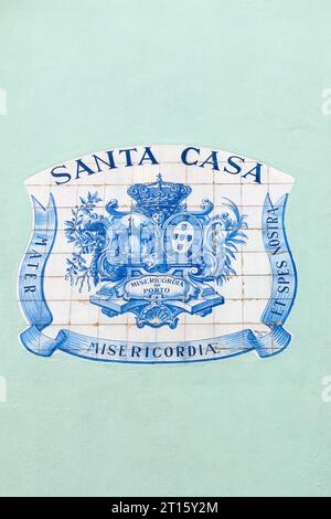 Signe fait avec des tuiles dans la façade de la Santa Casa. Les images ont un blason et des mots dans les bords. Banque D'Images