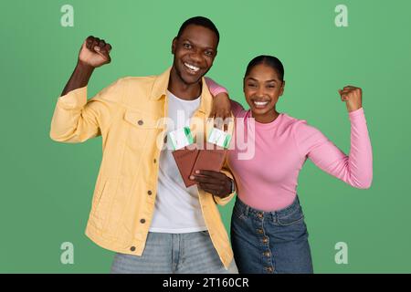 Jeunes touristes noirs excités montrant des billets et des passeports Banque D'Images