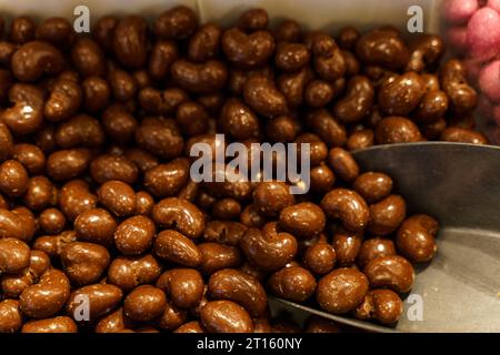 Il y a des bonbons sur le comptoir - cacahuètes recouvertes de chocolat et une cuillère. Magasin de bonbons. Banque D'Images