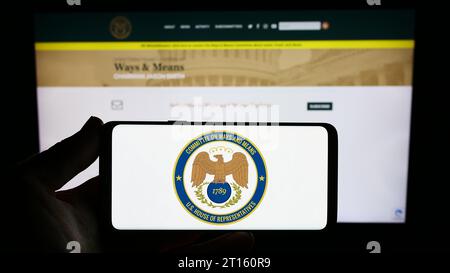Personne tenant le smartphone avec le sceau du Comité de la Chambre des États-Unis sur les voies et moyens en face du site Web. Concentrez-vous sur l'affichage du téléphone. Banque D'Images