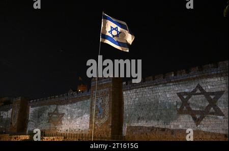 Vieille ville de Jérusalem, Israël. 11 octobre 2023. Un drapeau israélien flotte près des drapeaux projetés sur le mur de la vieille ville de Jérusalem après qu’Israël ait subi une attaque terroriste massive du Hamas à la frontière de Gaza, le mercredi 11 octobre 2023. Photo de Debbie Hill/ crédit : UPI/Alamy Live News Banque D'Images