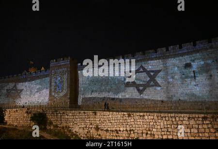 Vieille ville de Jérusalem, Israël. 11 octobre 2023. Les gens marchent sous un drapeau israélien projeté sur le mur de la vieille ville de Jérusalem après qu’Israël ait subi une attaque terroriste massive du Hamas à la frontière de Gaza, le mercredi 11 octobre 2023. Photo de Debbie Hill/ crédit : UPI/Alamy Live News Banque D'Images